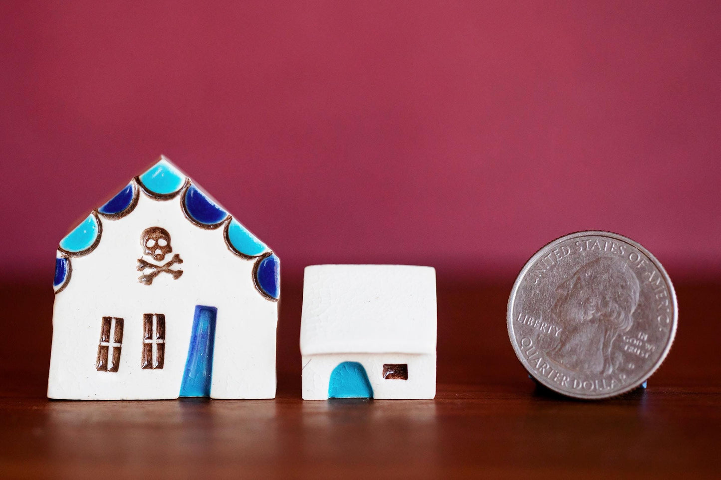 Tiny white ceramic houses with blue doors and a skull and crossbones stamp.