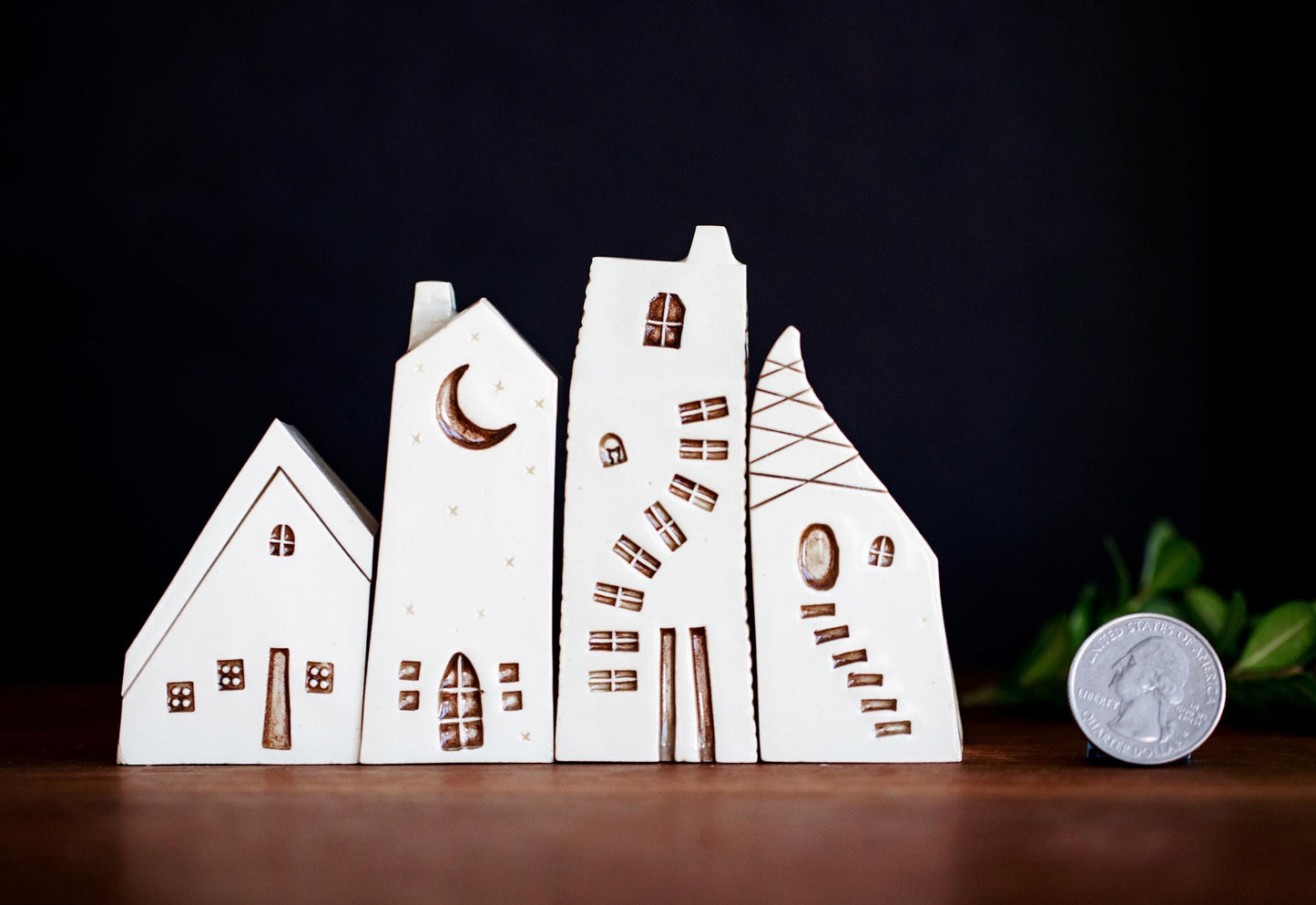 Weird and whimsical village of ceramic houses with moon and cat.