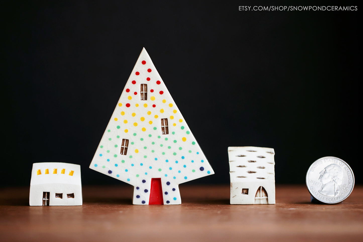 A set of two tiny ceramic houses with a medium sized ceramic tree house with a rainbow of dots.