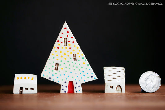 A set of two tiny ceramic houses with a medium sized ceramic tree house with a rainbow of dots.