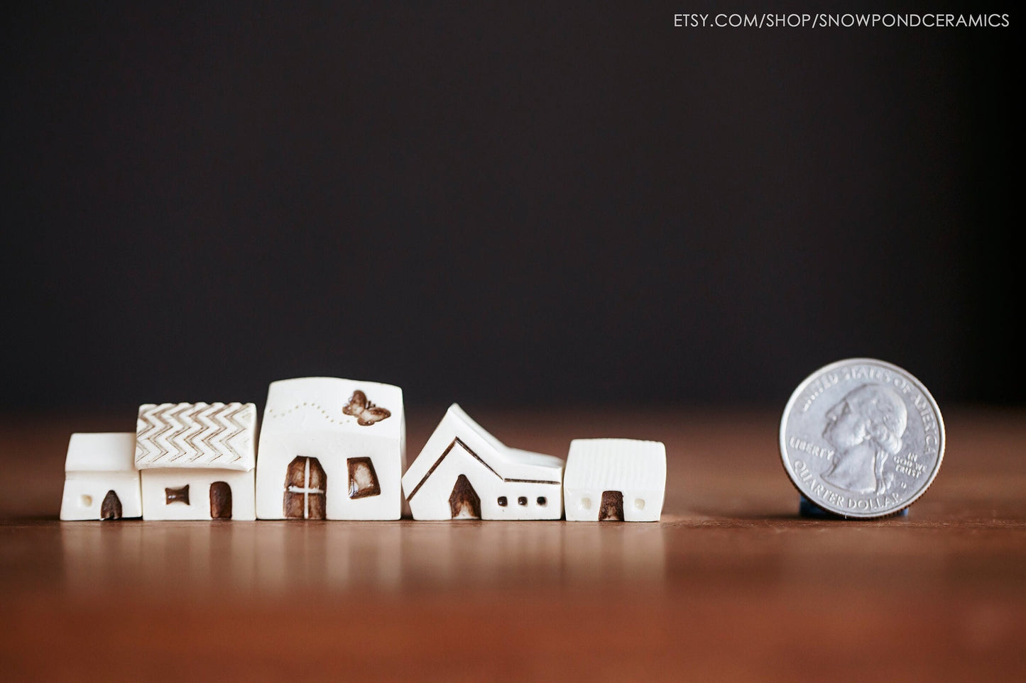 A set of five teeny tiny white ceramic houses with windows, doors, and a butterfly.