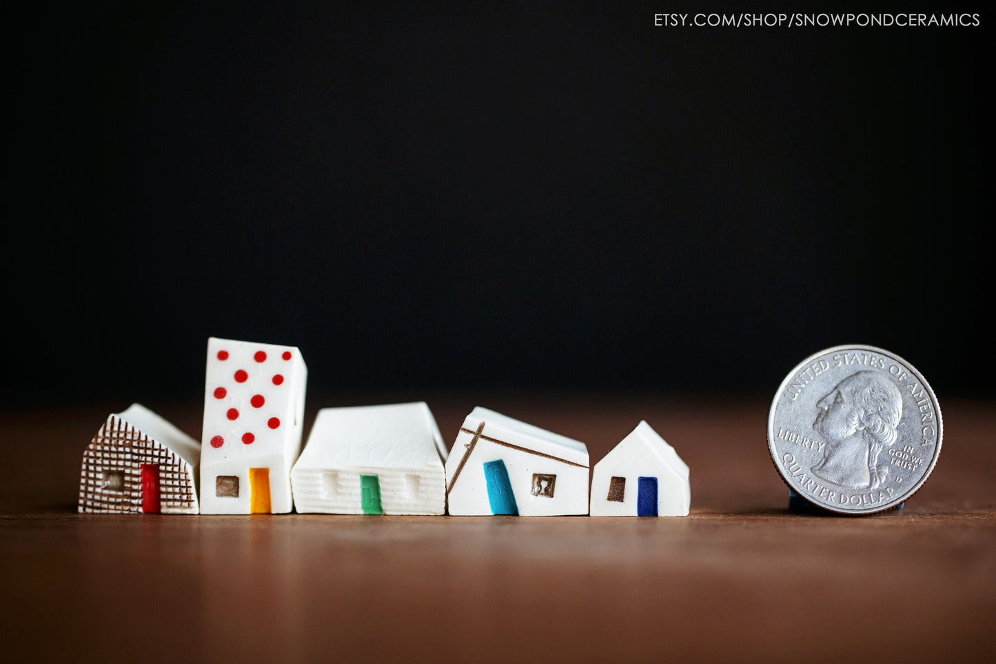 A set of five miniature ceramic houses with a rainbow of doors and a cat in the window.