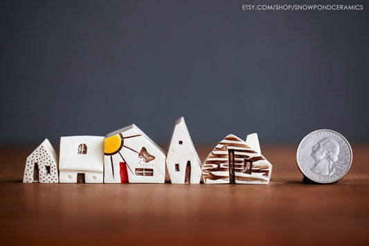 Village of five small ceramic houses with different textures and a butterfly.