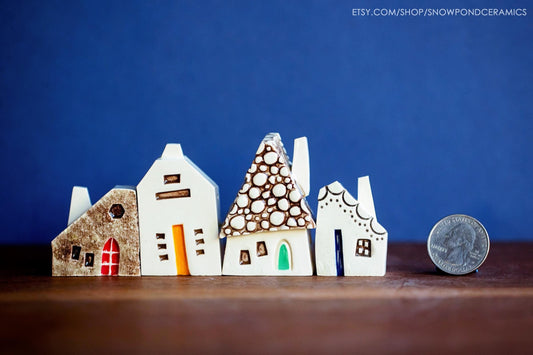 Quirky miniature ceramic village of houses with stucco, cobblestone, and yellow doors.