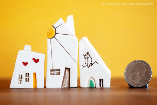 Tiny white ceramic houses with red hearts, a sunshine and an owl stamped on them.