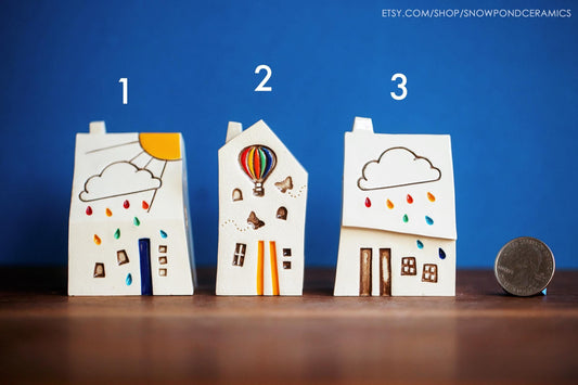 Miniature ceramic house with a cloud and rainbow raindrops.